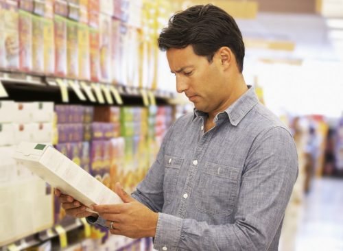 Homme lisant l'étiquette nutritionnelle de boîte à céréales dans un supermarché