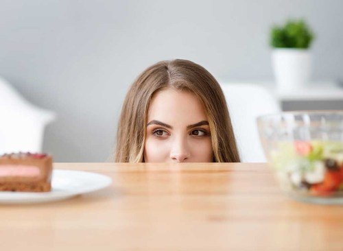 Femme qui veut de la malbouffe plutôt qu'une salade - Comment vaincre le plateau de la perte de poids