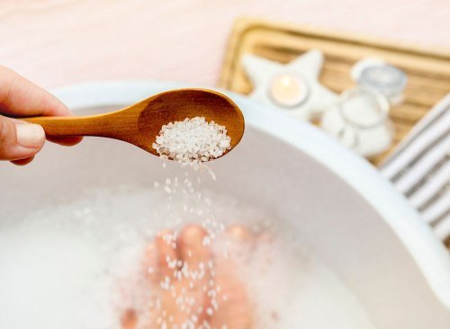 Femme versant du sel d'Epsom dans le bain - comment se débarrasser d'un ventre gonflé en 24 heures