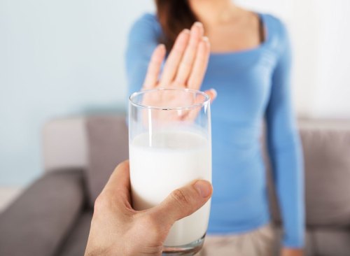 Une femme tend la main et dit non à un homme en lui offrant un verre de lait - comment se débarrasser d'un ventre gonflé en 24 heures