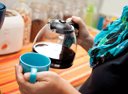 femme tenant une cafetière et une tasse - comment se débarrasser d'un ventre gonflé en 24 heures