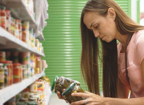 Femme décidant entre deux aliments et lisant l'étiquette d'un aliment