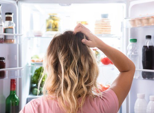 femme debout près du réfrigérateur affamé et confus