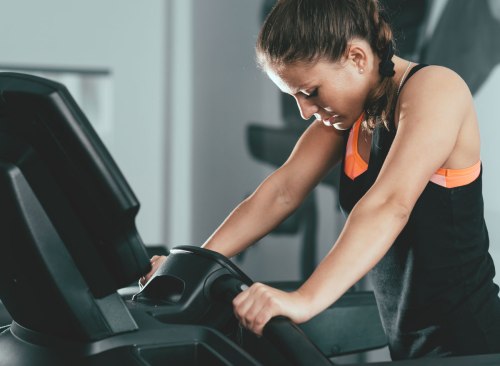 Fatigué femme au gymnase luttant pour terminer la formation de tapis roulant