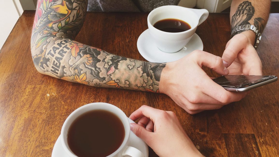 personne tatouée, boire du café à une table