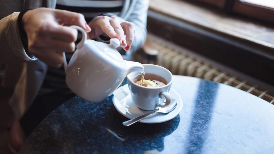 quelqu'un versant du thé dans une tasse