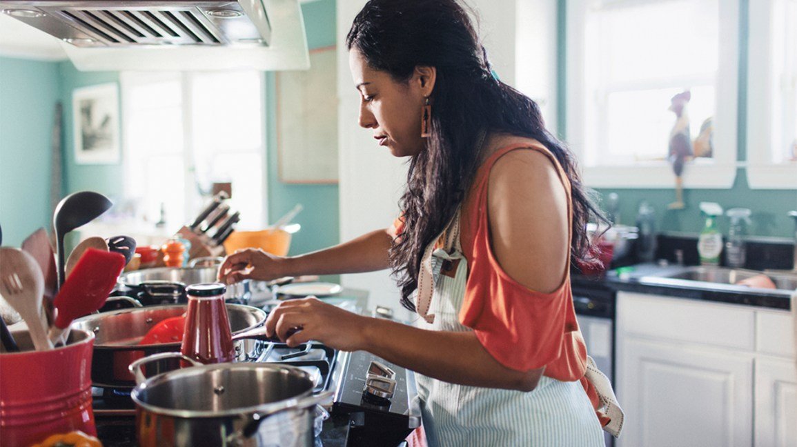une femme avec un tablier cuisinant à la cuisinière
