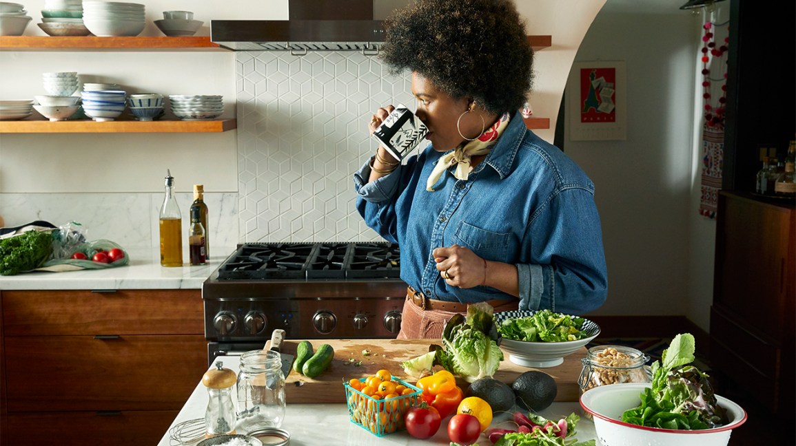 Cétose : Femme buvant dans une tasse et debout près d'une table contenant des tomates et d'autres produits