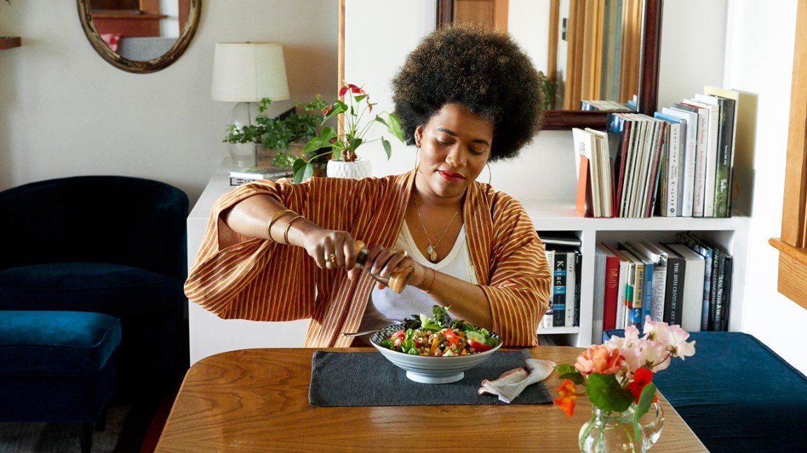 Woman cracking pepper sur une salade à la maison
