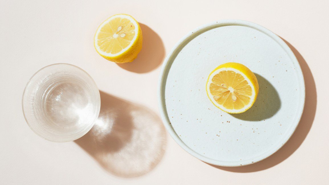 un verre d'eau avec un citron coupé en deux
