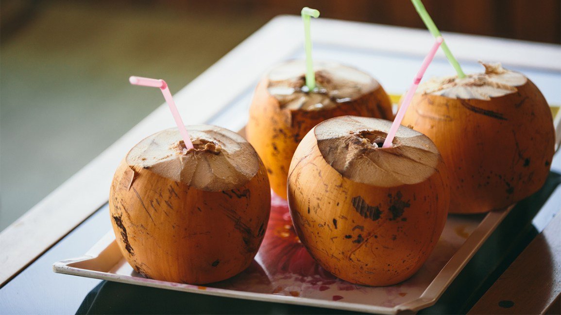 L'eau de coco : Quatre noix de coco ouvertes avec des pailles en eux