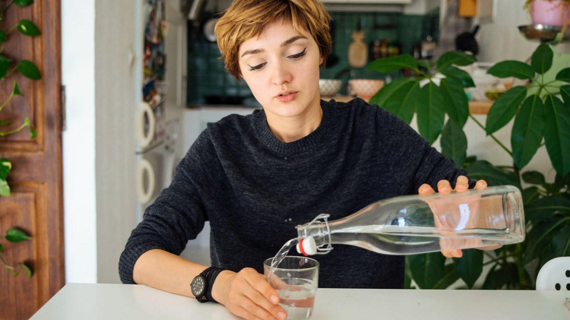 femme versant de l'eau d'une bouteille en verre
