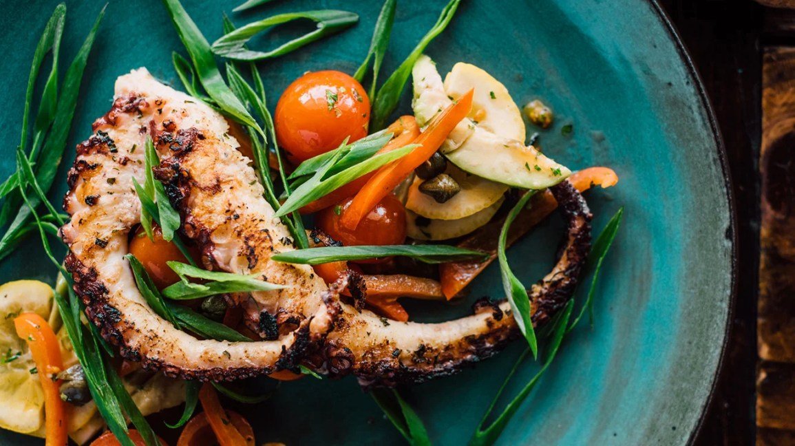 Poulpe sur une assiette avec quelques légumes.