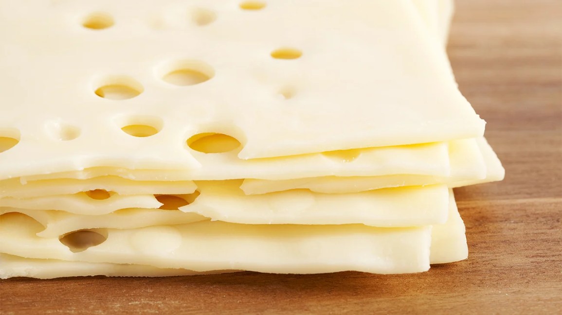 tranches de fromage suisse empilées sur une planche à découper en bois