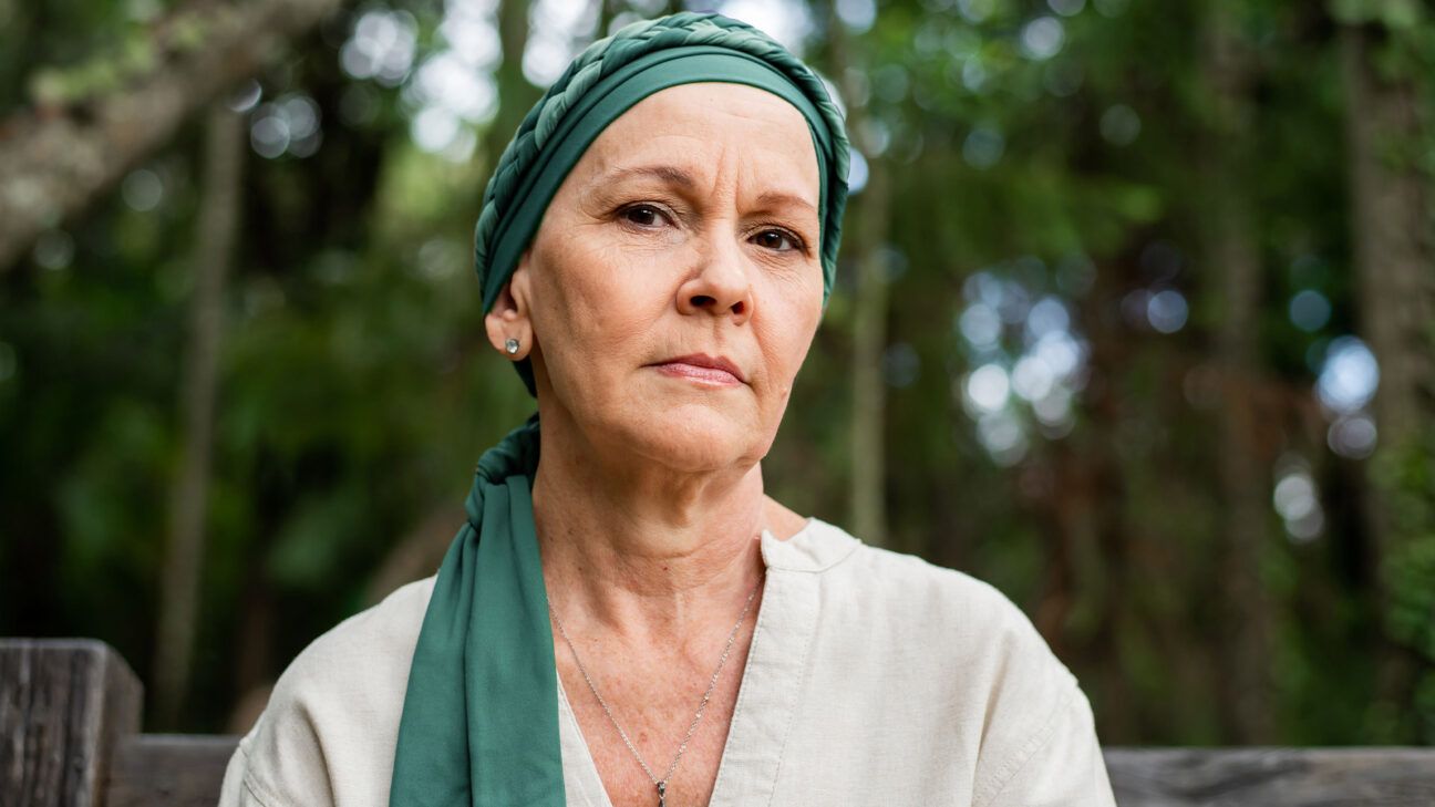 Une femme avec un foulard vert regarde la caméra