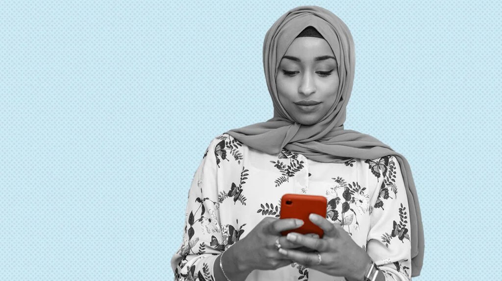 photo en noir et blanc d'une femme portant un foulard utilisant un téléphone rouge pour des applications de suivi de la fertilité, isolée sur fond bleu