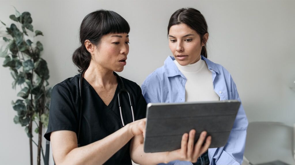 Un médecin montre quelque chose à un patient sur l'écran d'une tablette.