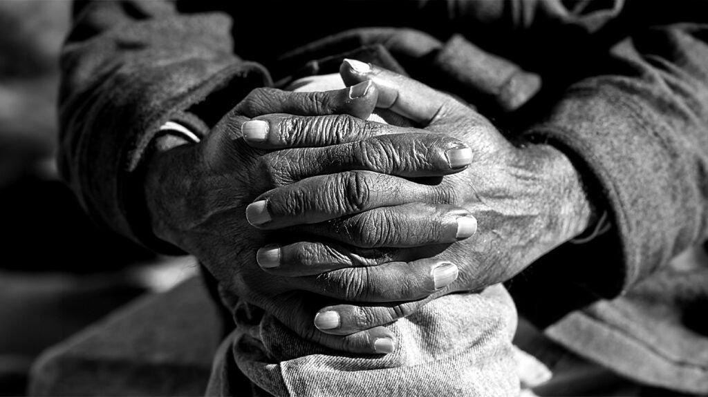 photo en noir et blanc des mains d'une personne âgée serrant son genou