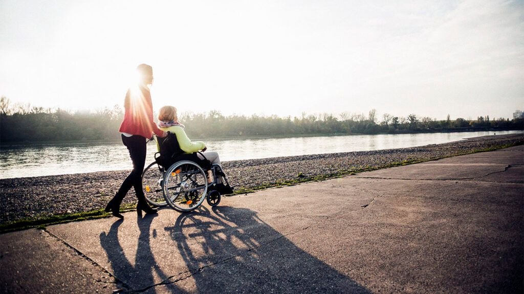 Une personne poussant une personne atteinte de SEP dans un fauteuil roulant.-2