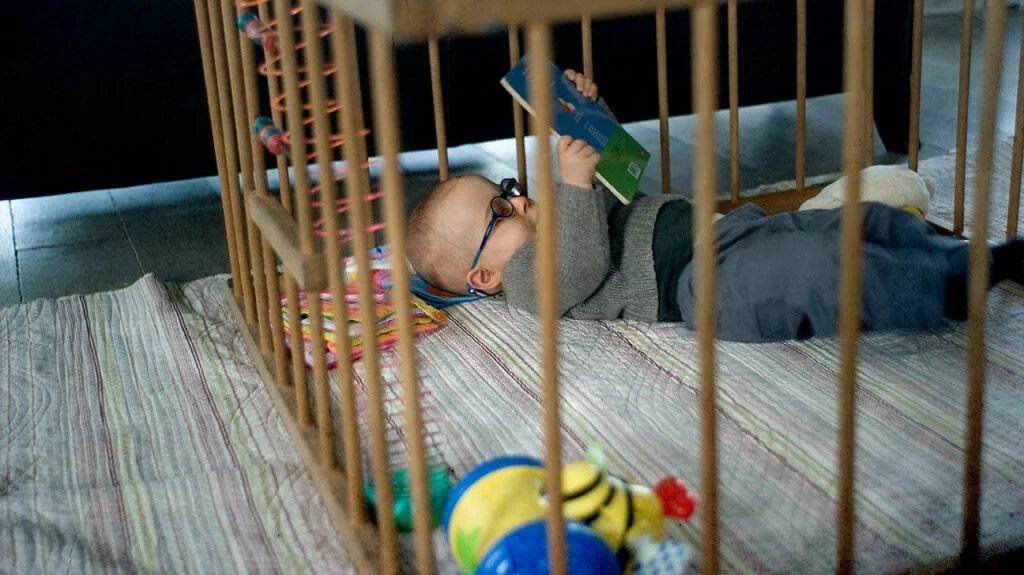 Un bambino con gli occhiali sdraiato che legge un libro